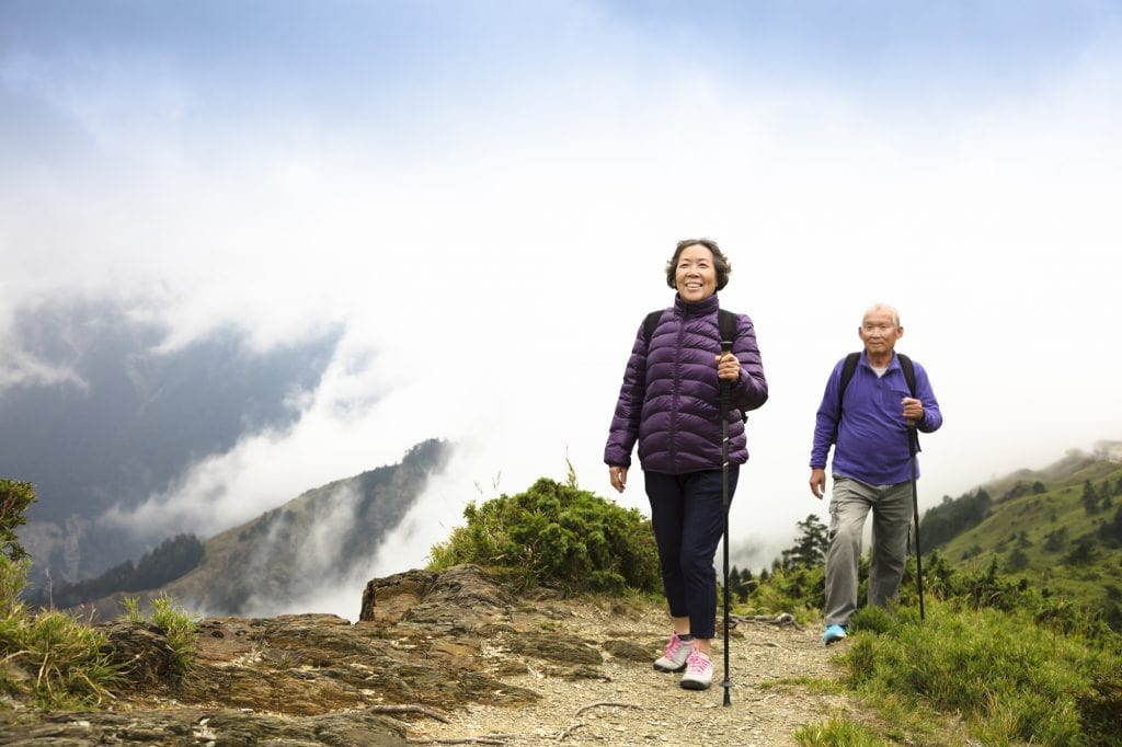 happy asian senior couple hiking on the mountain